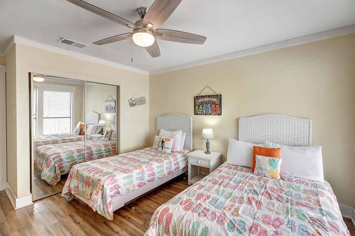 Your cheerful bedroom features comfortable twin beds with coastal charm, hardwood floors, and a ceiling fan for restful nights.