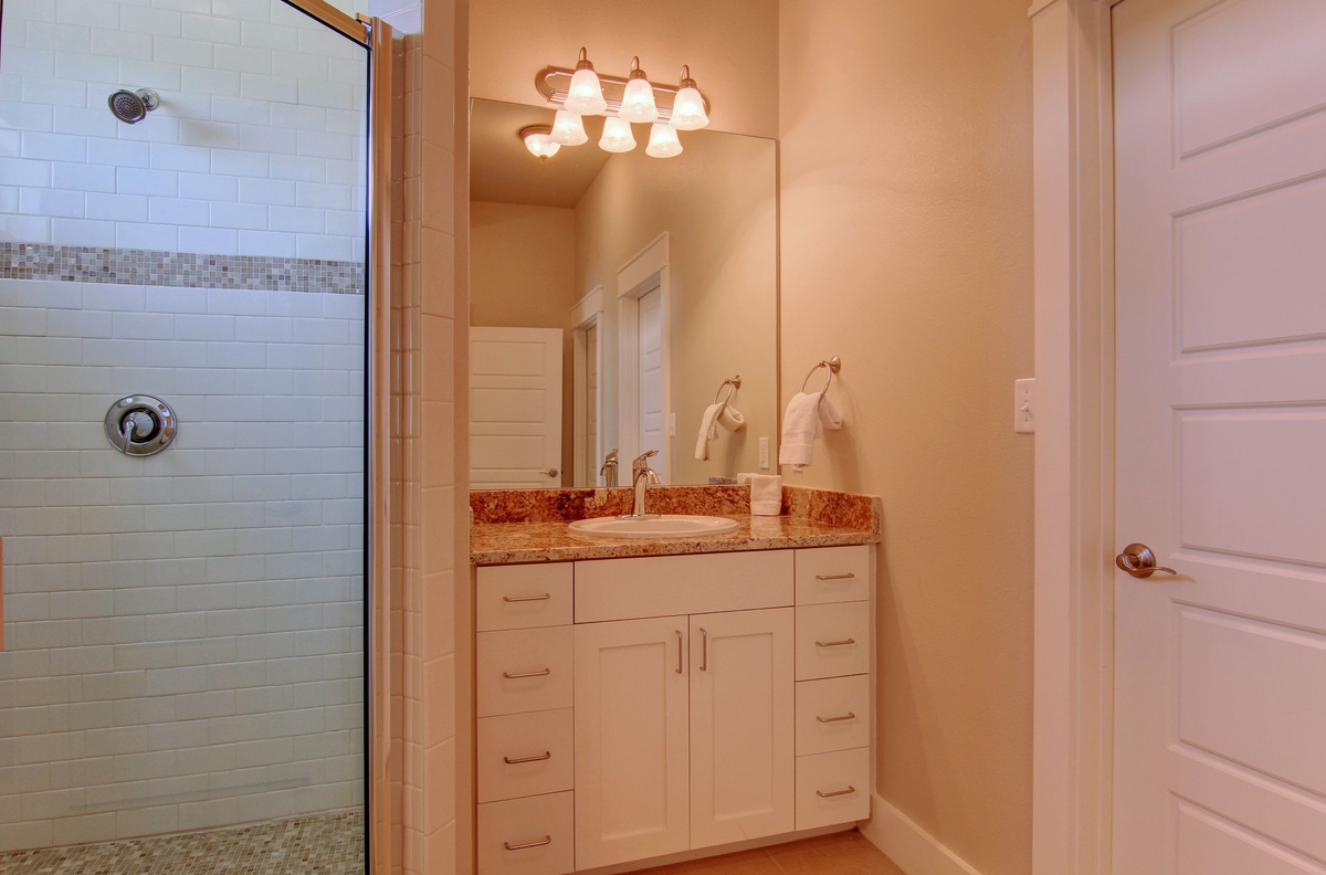 Refresh in your elegant bathroom with subway tile shower, granite vanity, and warm lighting for your morning routine.