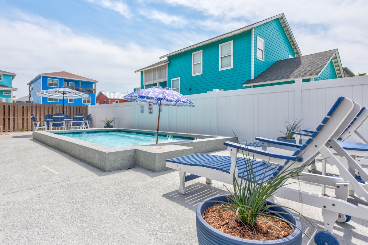 Relax by your private pool on comfortable lounge chairs, surrounded by colorful beach houses in this peaceful coastal setting.