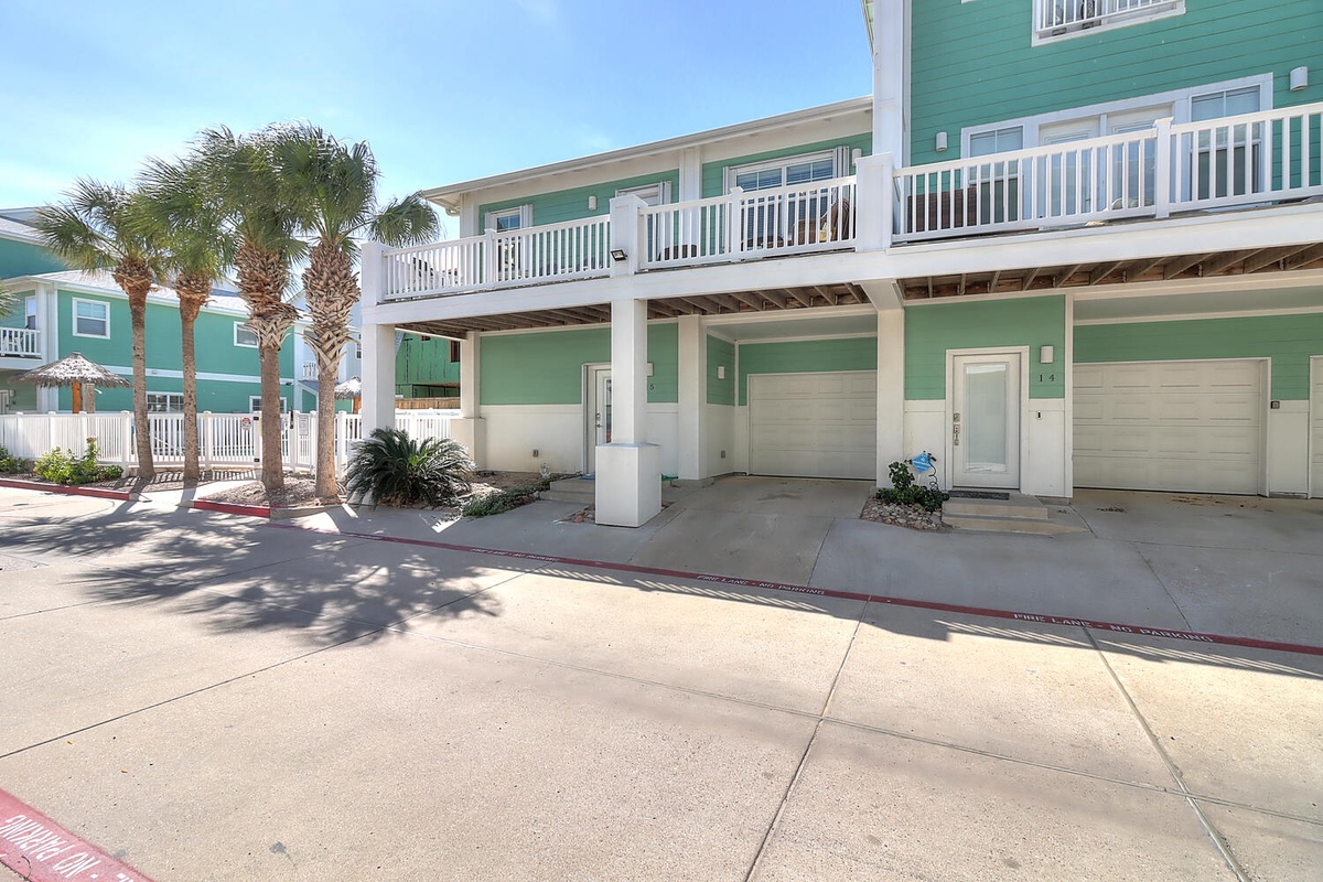 Charming coastal property featuring tropical palm landscaping, covered parking, and balconies overlooking a peaceful residential area.