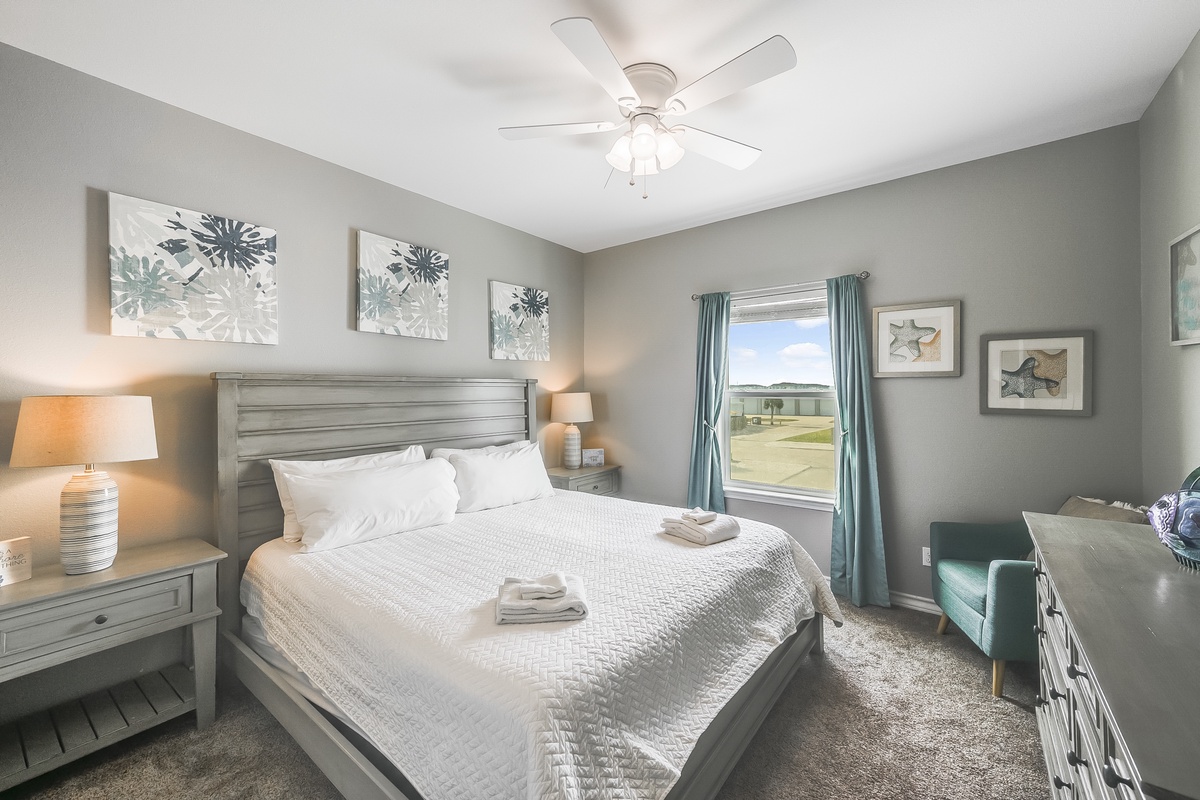 Sink into your comfortable bed with soft linens and enjoy the gentle ceiling fan breeze in this thoughtfully appointed bedroom.