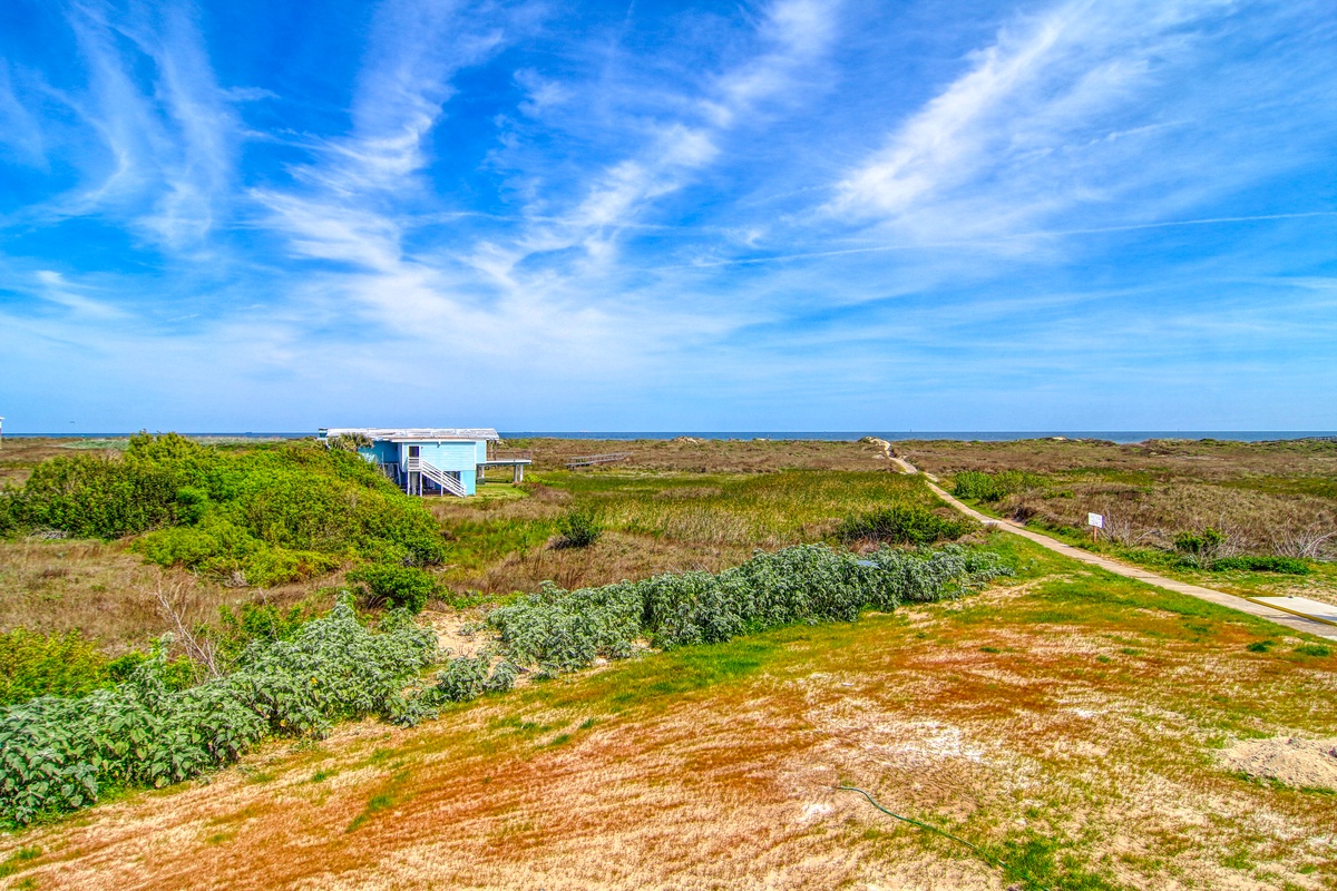 Coastal property surrounded by pristine natural dunes and winding pathways leading to the shoreline.