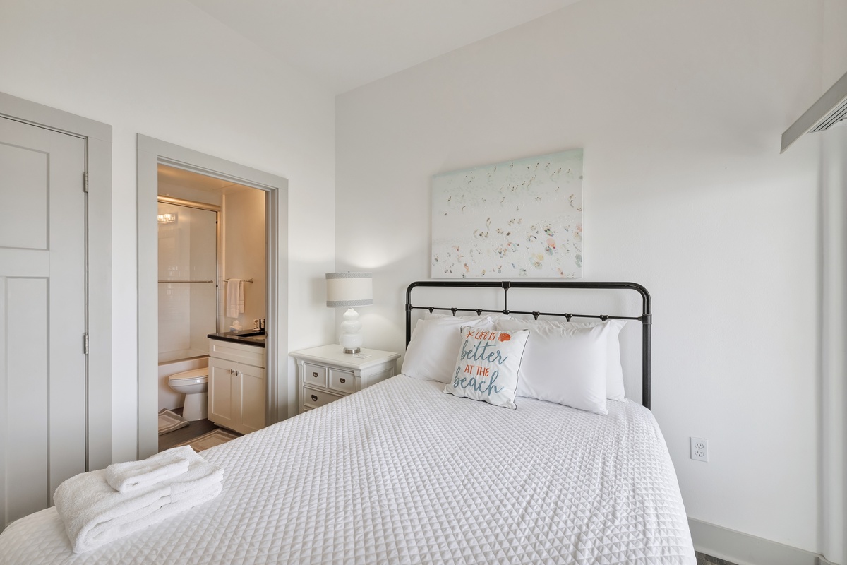 Drift off in this cozy bedroom with its plush bedding, charming coastal touches, and bright ensuite bathroom just steps away.