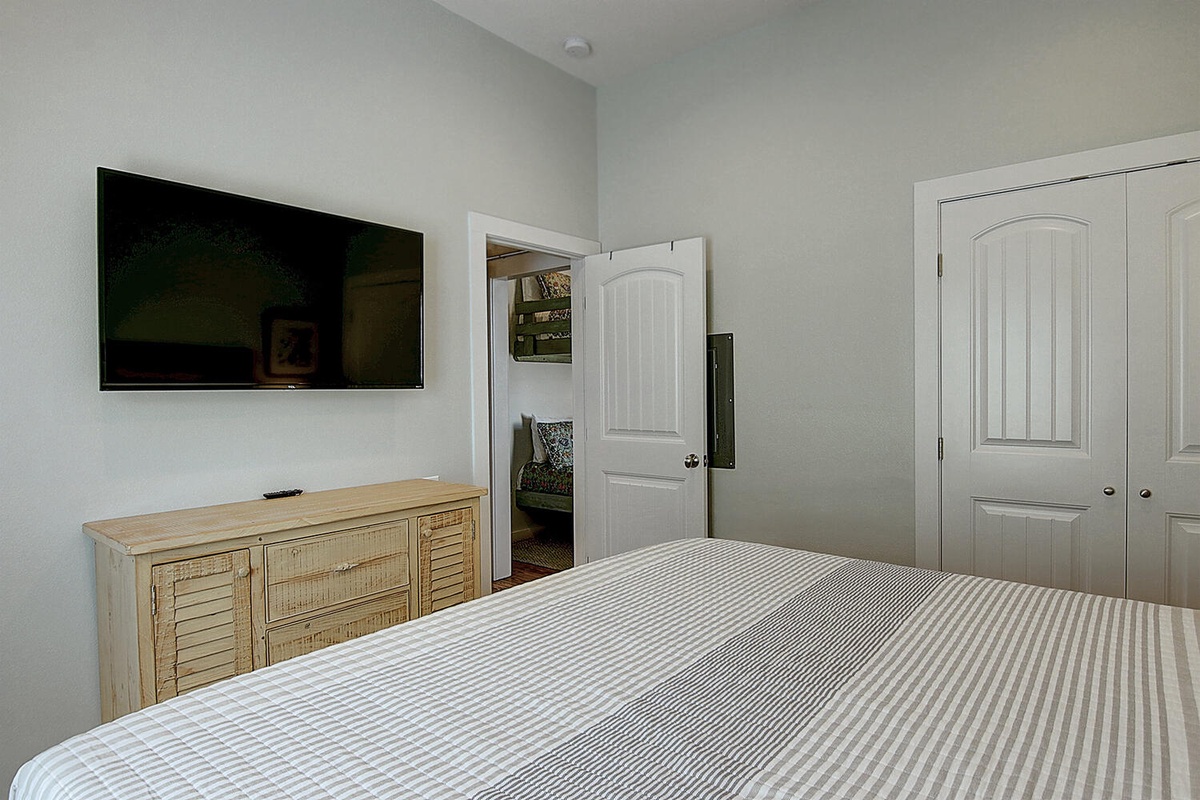 Unwind in your peaceful bedroom with cozy striped bedding, flat-screen TV for entertainment, and stylish coastal-inspired furnishings.