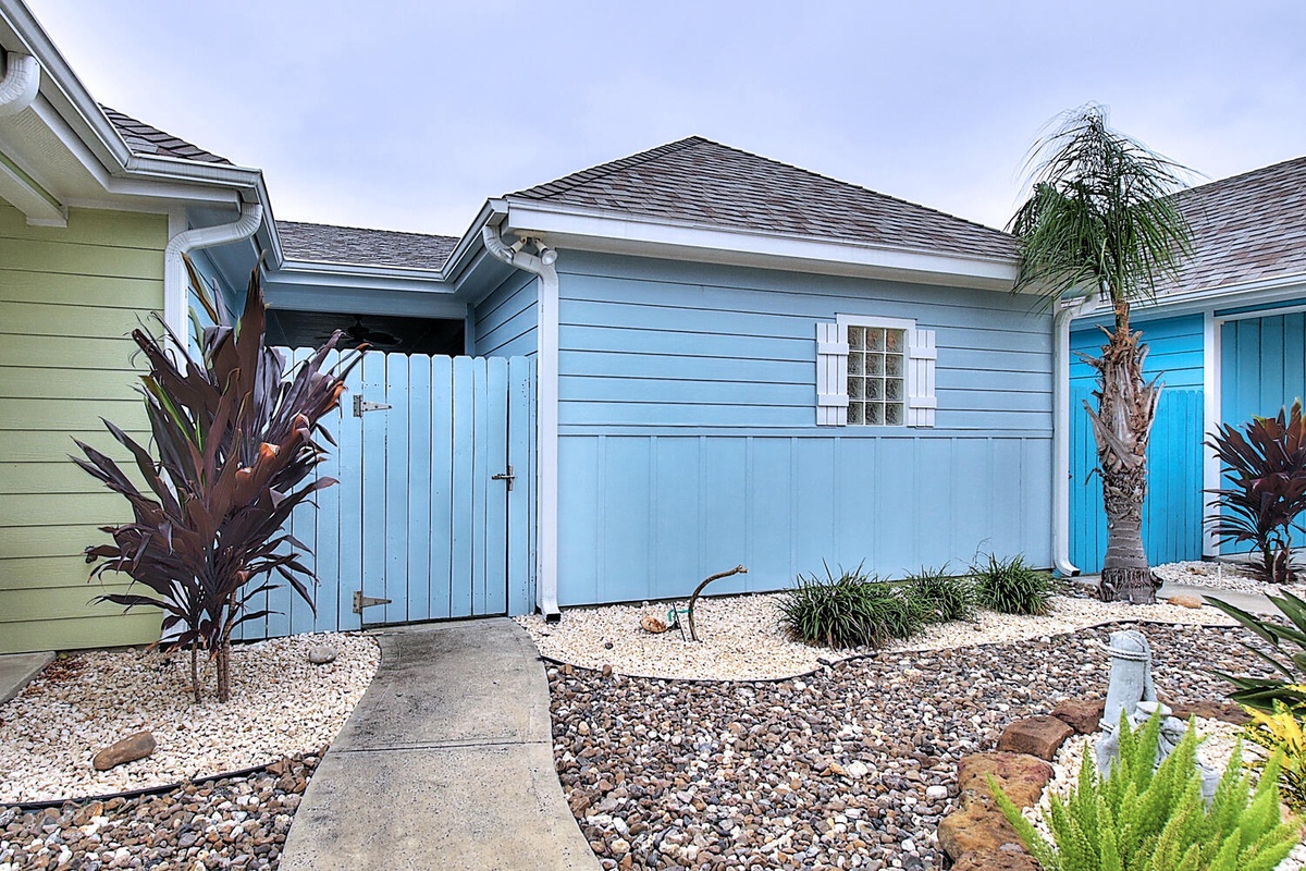 Colorful coastal cottage with tropical landscaping and palm trees creates a charming beachside retreat setting.
