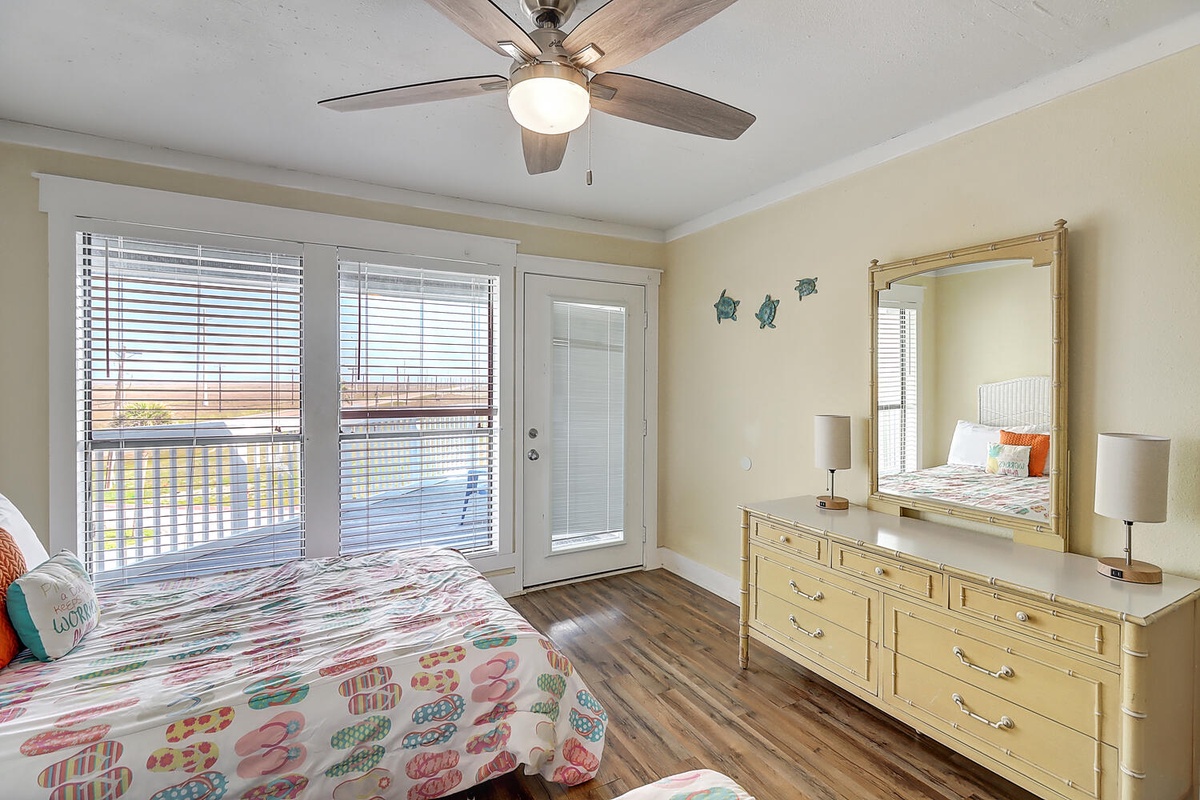 Wake up in your bright bedroom with coastal touches, complete with ceiling fan and direct balcony access for morning fresh air.