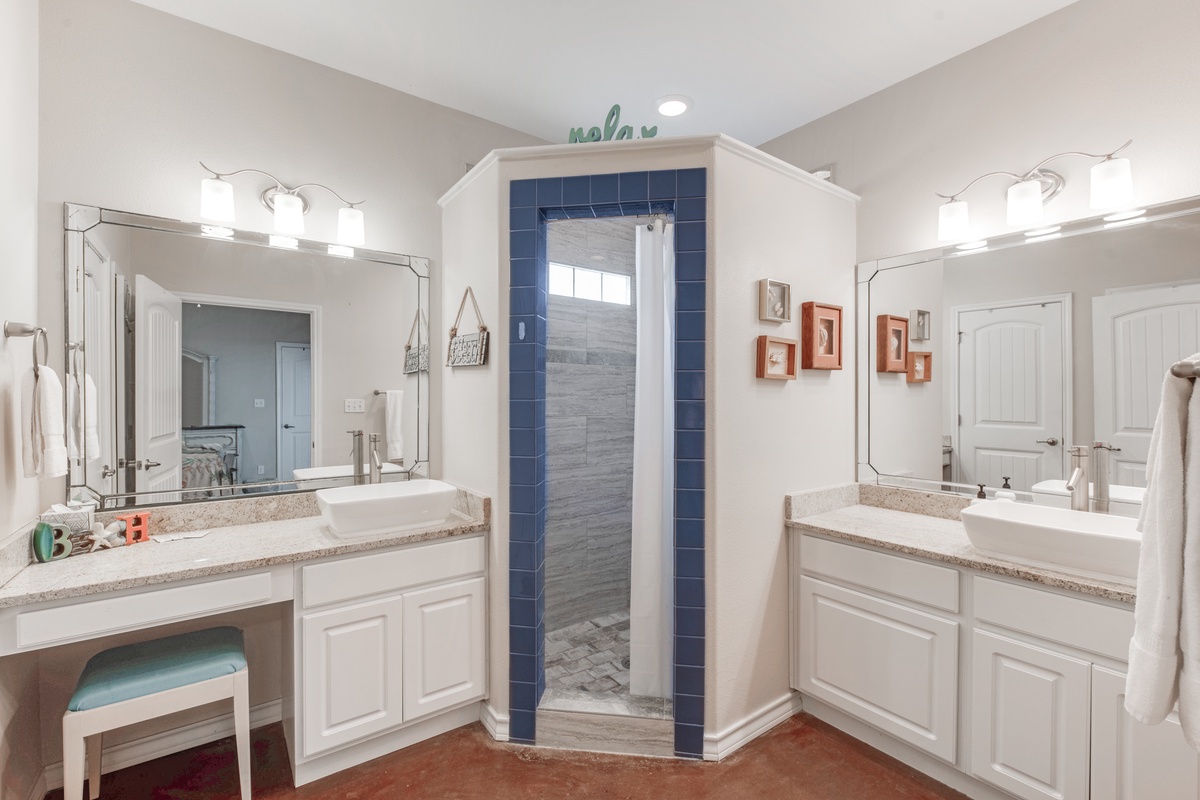 Refresh in your spacious dual-vanity bathroom with bright lighting and a stunning walk-in shower featuring modern blue tile accents.