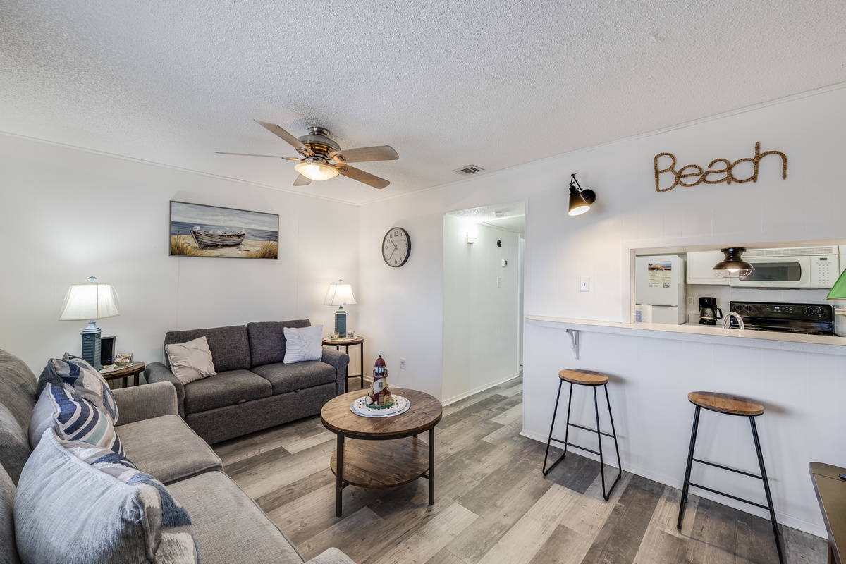 Relax in your coastal-themed living space with comfy seating and open kitchen perfect for beach getaway meals.