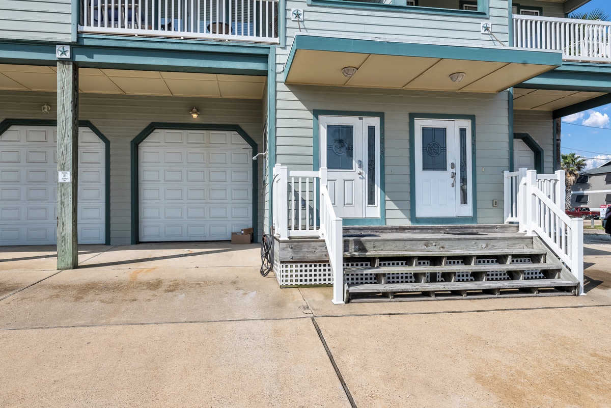 Charming coastal property building with convenient parking and welcoming entrance featuring nautical-themed doors and covered balconies above.