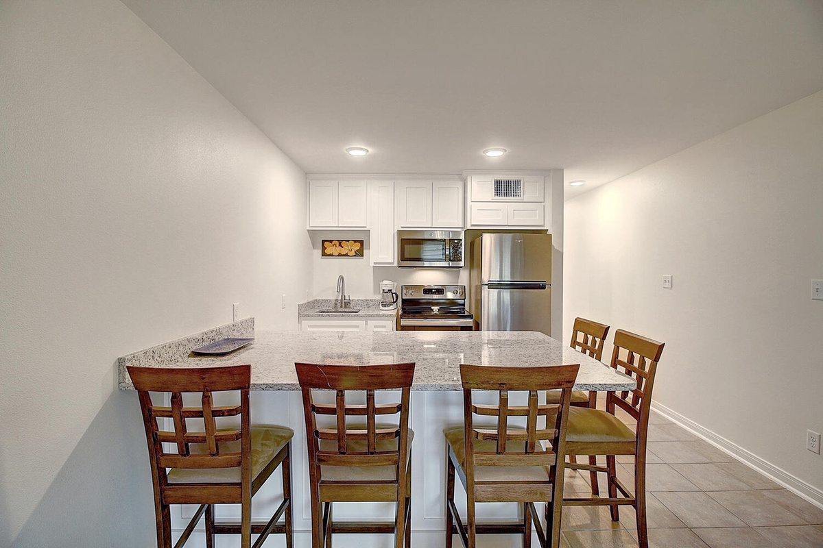 Your fully-equipped kitchen awaits with granite counters, stainless appliances, and breakfast bar seating for casual meals and morning coffee.