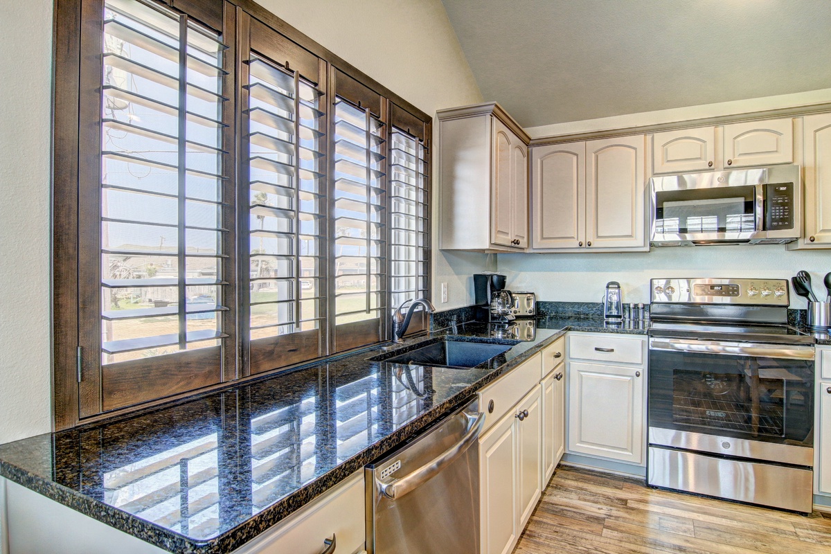Your fully-equipped kitchen awaits with granite counters, stainless appliances, and plantation shutters filtering warm natural light for perfect morning coffee moments.