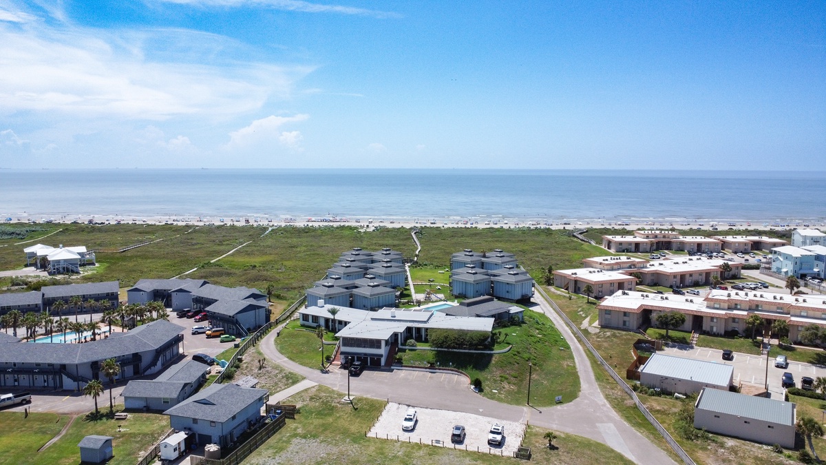 Coastal community aerial view showcasing beachfront vacation homes with ocean access and nearby residential developments.