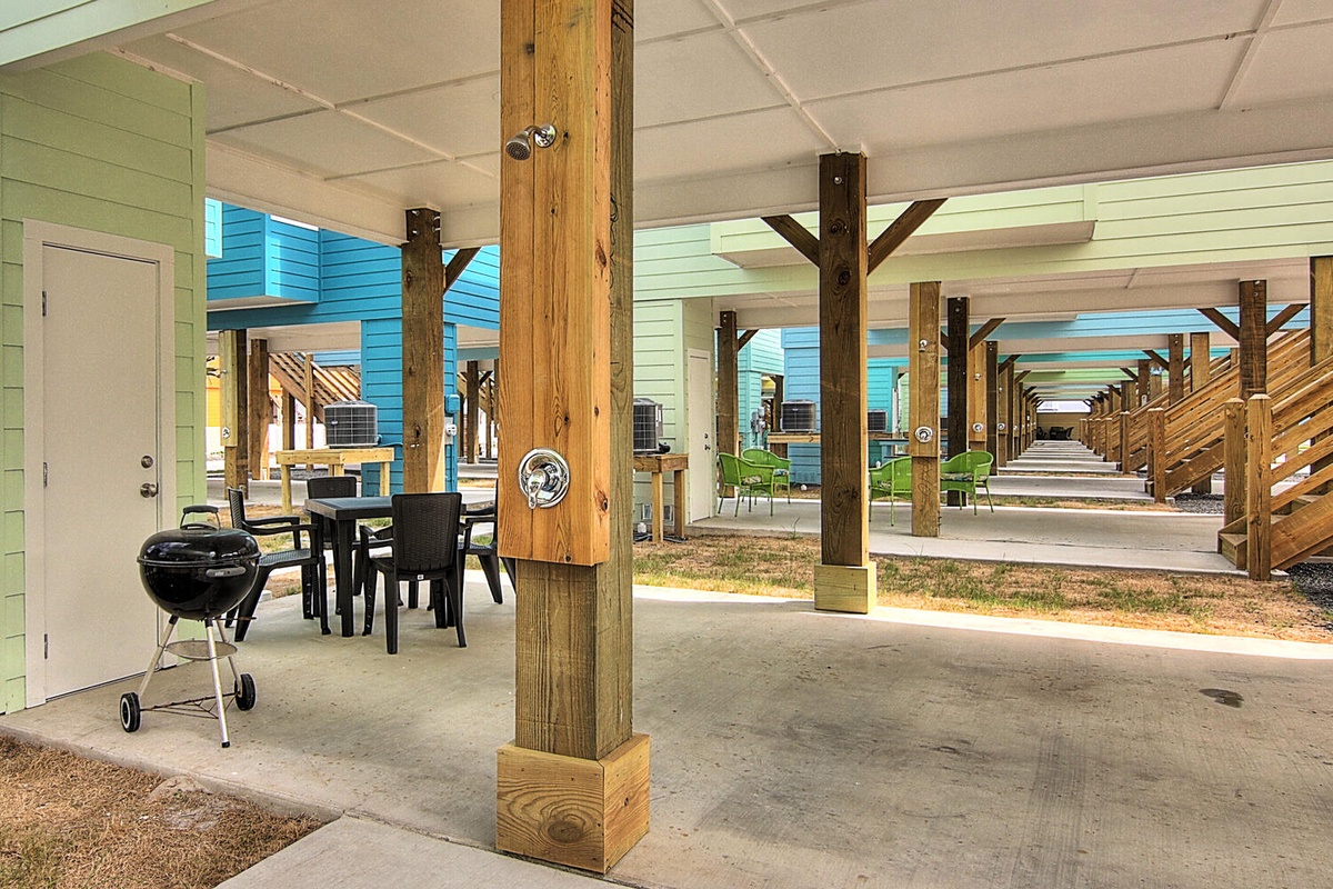 Your covered outdoor space features dining tables and a charcoal grill, perfect for gathering with family and friends.