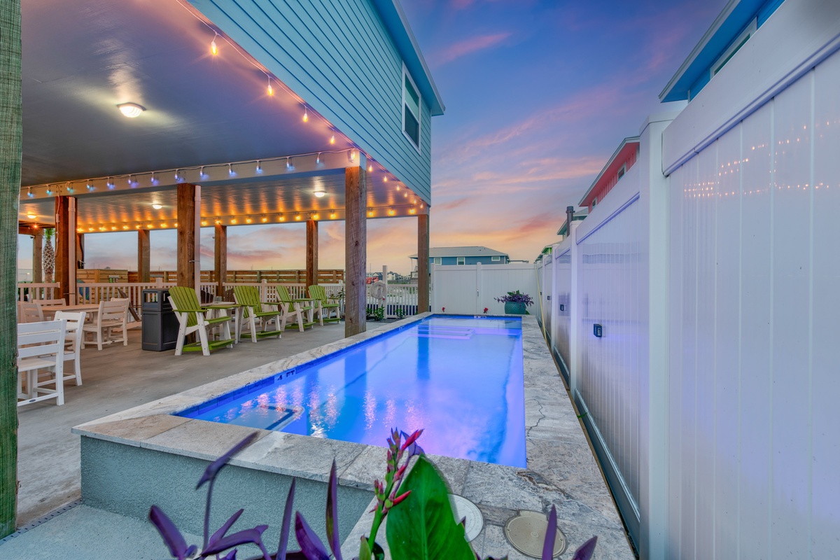 Stunning twilight views frame this illuminated pool and covered patio area, perfect for evening relaxation at this coastal vacation rental.