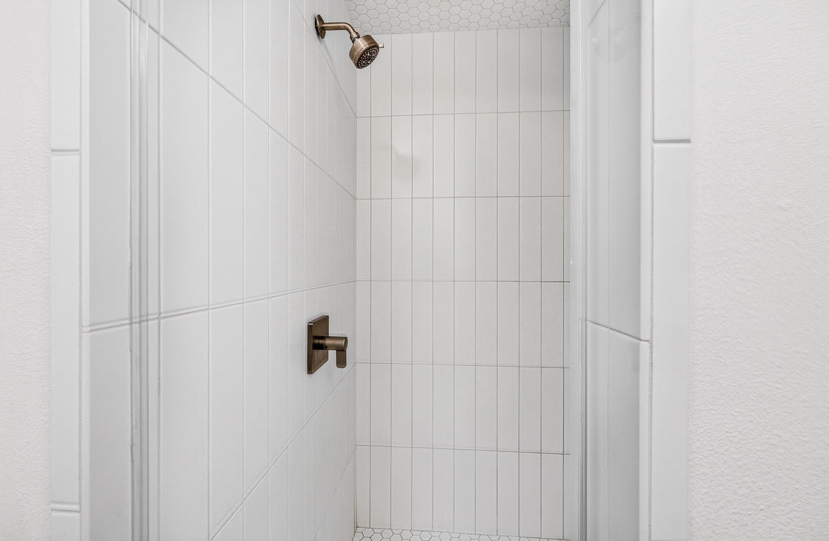 Refresh in your private walk-in shower with elegant white tiling and a rainfall showerhead—clean, modern, and ready for you.