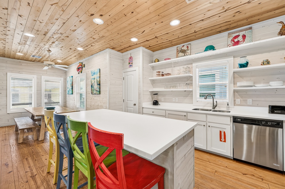 Your kitchen awaits with bright coastal charm, featuring a spacious island for gathering, open shelving filled with beach treasures, and playful seating that invites laughter over morning coffee or evening meals.