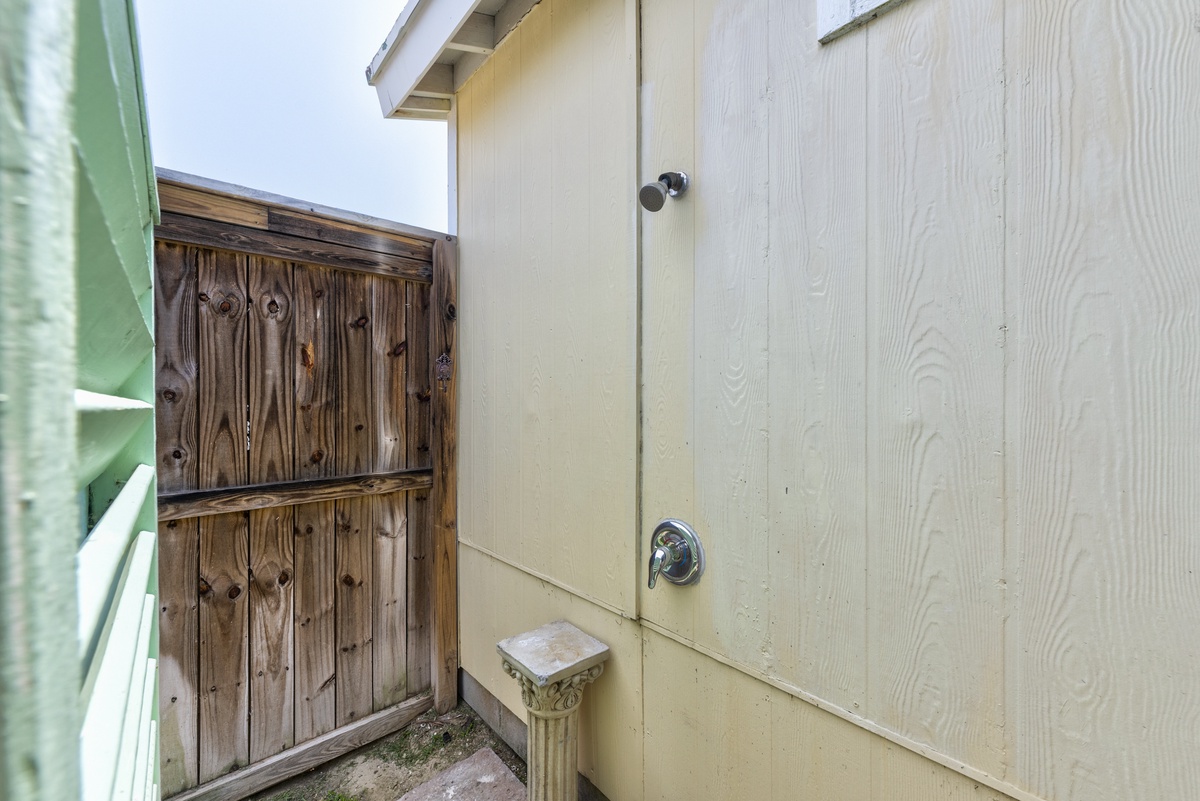 The property features an outdoor shower area with a private wooden fence enclosure, perfect for rinsing off after a day at the beach or pool.