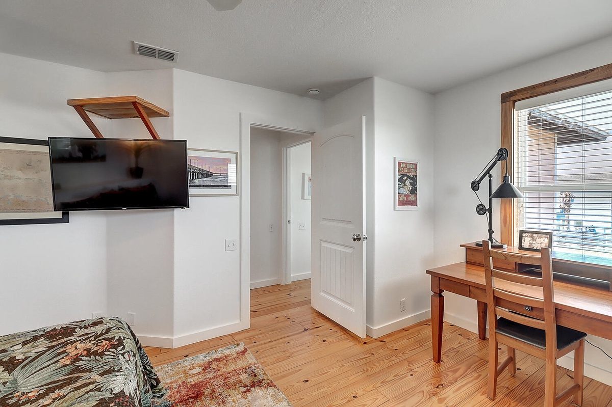 Your bright workspace features warm wood floors, a wall-mounted TV, and a dedicated desk area where you can stay productive during your stay.