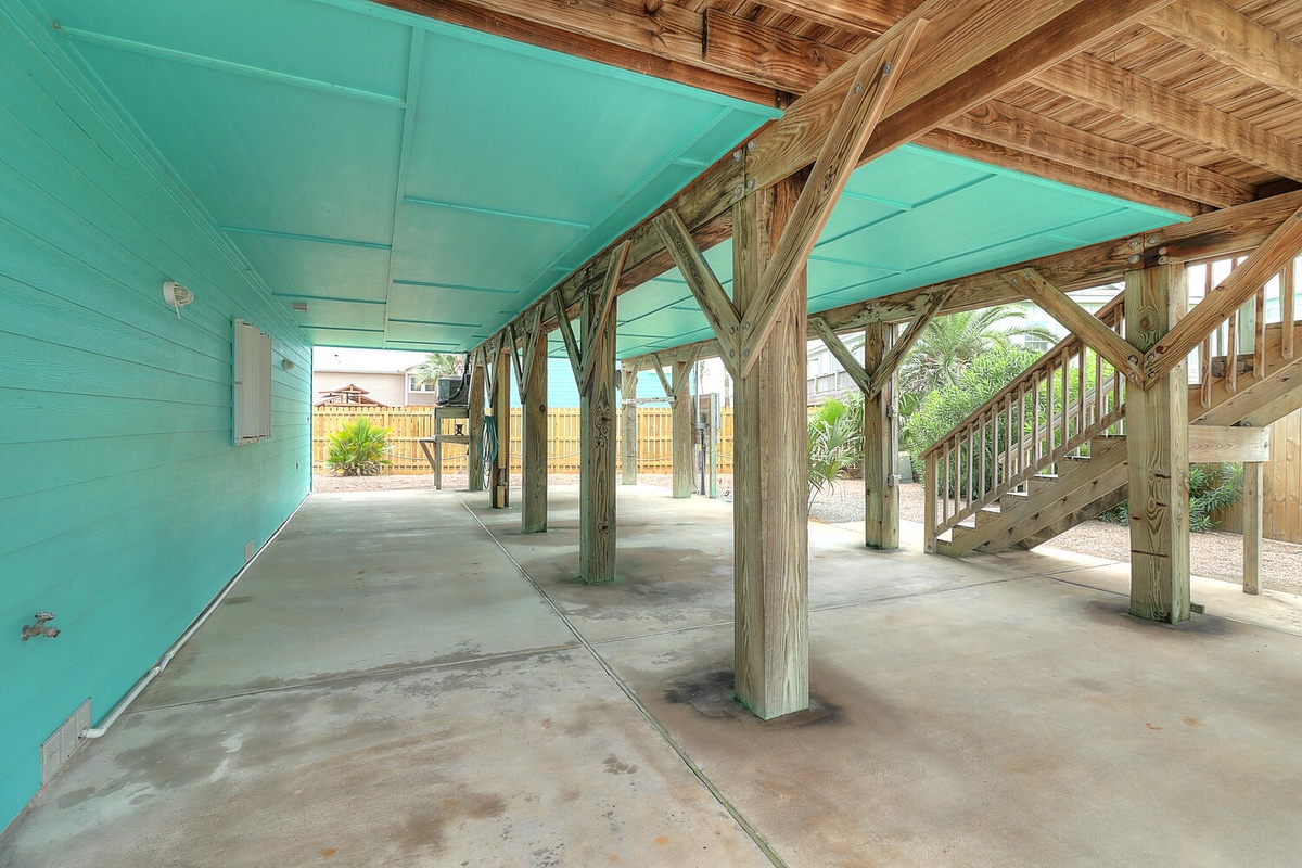 Your covered parking area keeps vehicles protected while showcasing the property's distinctive turquoise and natural wood coastal charm.