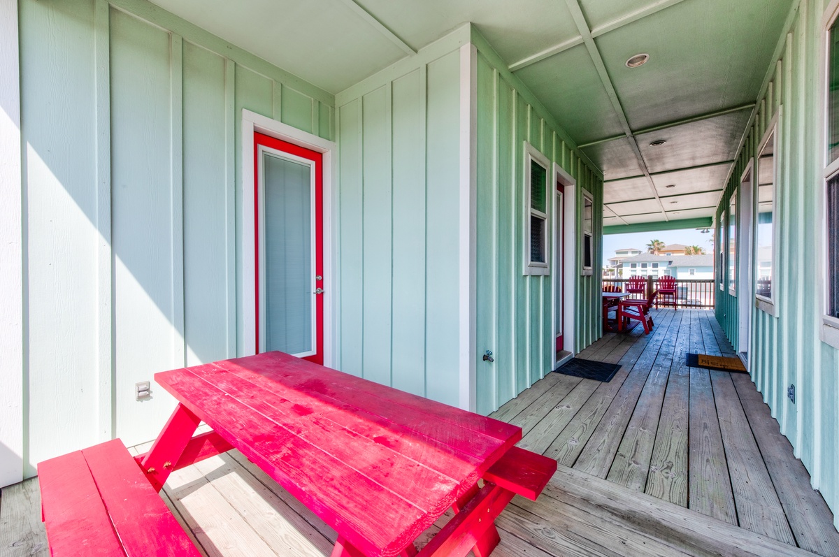 Relax on your private covered porch with a vibrant red picnic table, perfect for morning coffee or evening meals.