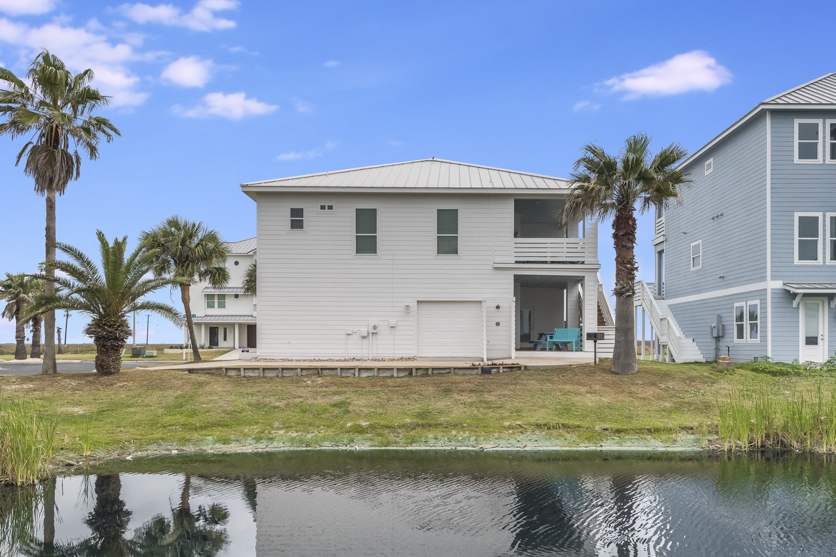 Modern waterfront home with tropical palms and peaceful canal views in a coastal neighborhood setting.