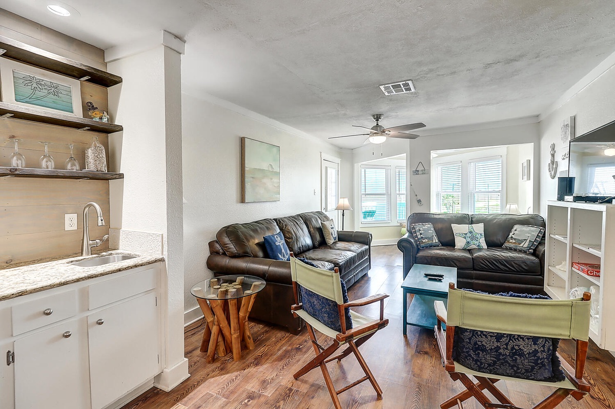 Relax in your bright coastal-themed living space with plush leather seating and charming open kitchen perfect for vacation meal prep.