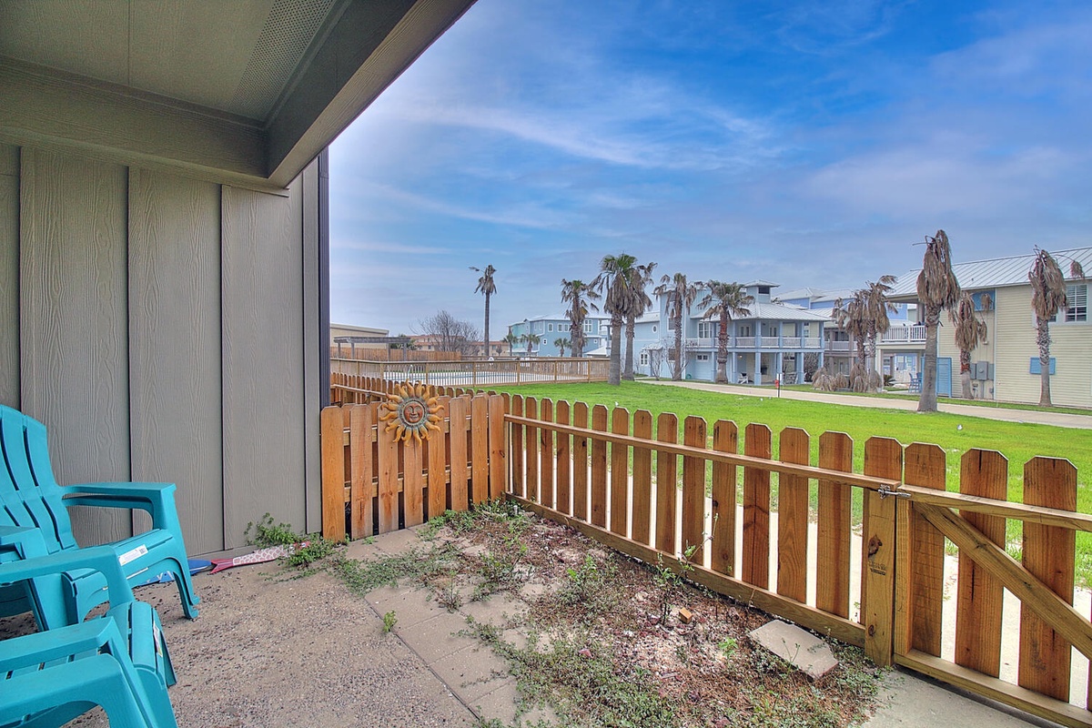 Your private patio features bright turquoise seating and opens to a green lawn area, creating a peaceful outdoor retreat.