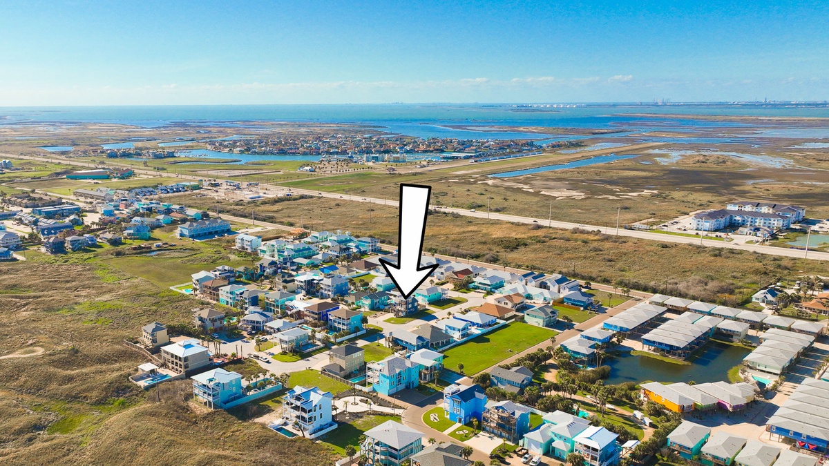 Aerial view of coastal property location nestled among colorful beach homes with expansive ocean and wetland views nearby.
