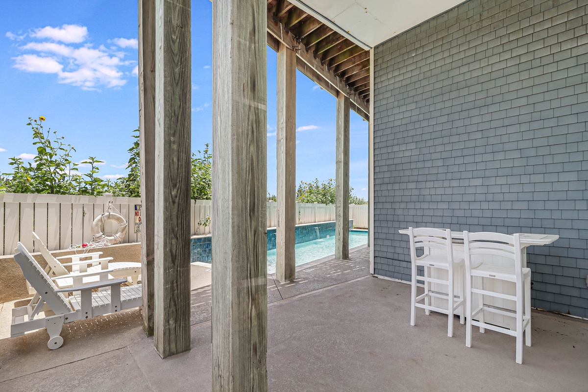 Relax on your private covered patio with pool access. White outdoor furniture awaits your morning coffee or evening cocktails by the water.