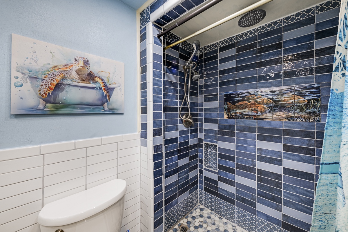 Fresh coastal colors, granite countertops, and a beautifully tiled shower bring beachside charm to this full bathroom.