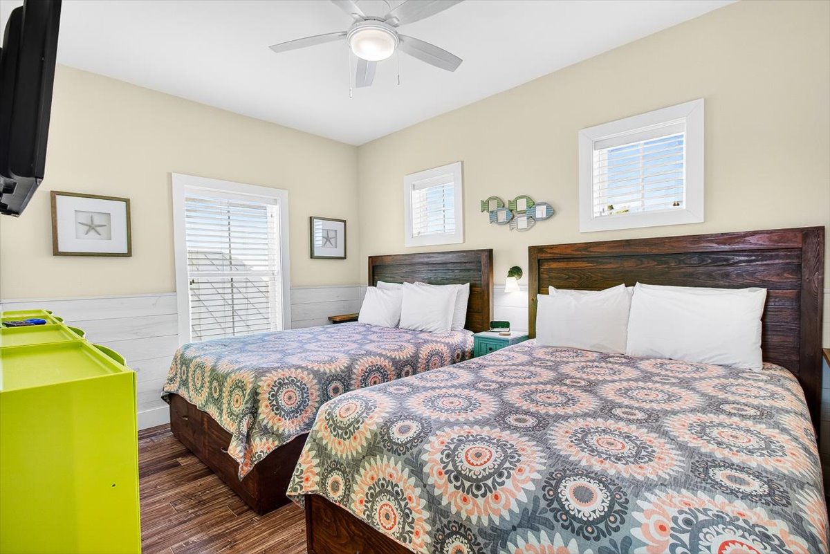 Two queen beds with rustic wooden headboards offer comfortable rest under gentle ceiling fan breezes in your bright, cheerful bedroom.