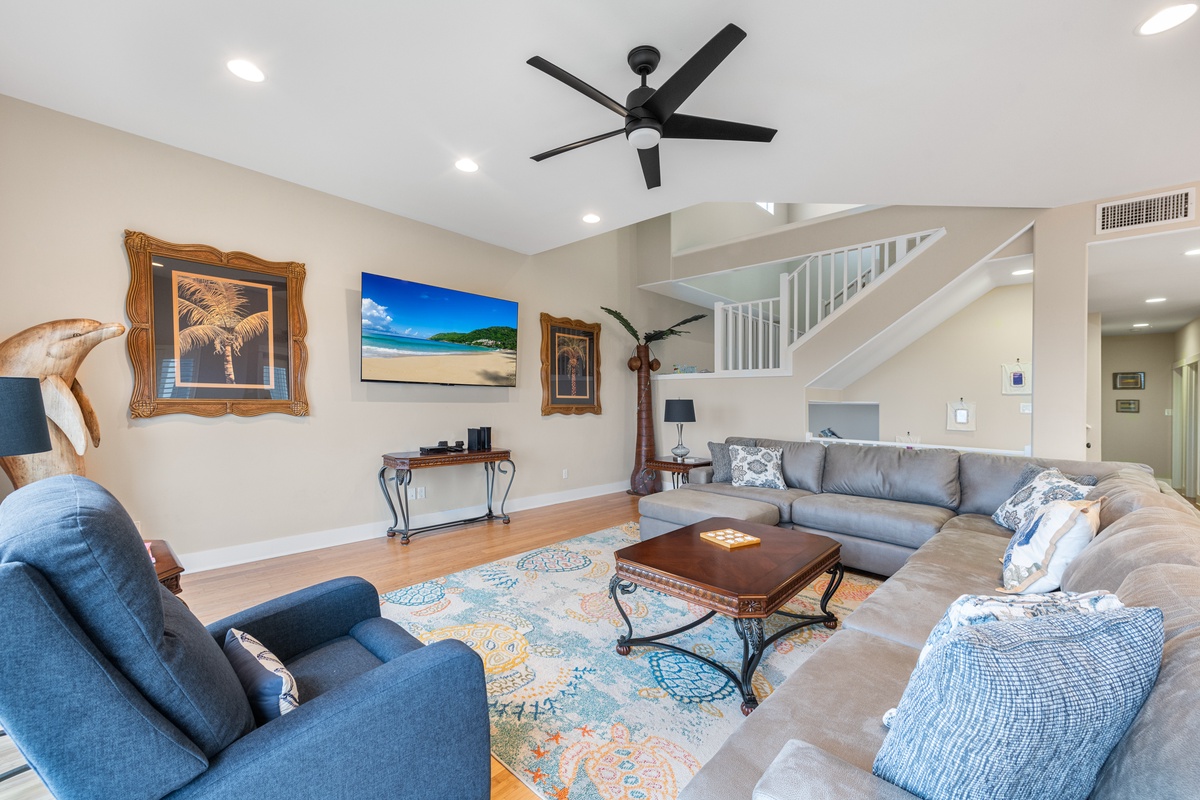 Unwind in your spacious living room featuring comfortable seating, coastal decor, and a ceiling fan to keep you cool.
