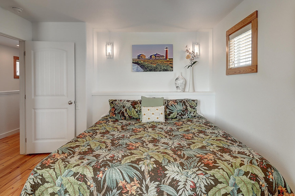 Your cozy bedroom features tropical bedding and coastal artwork, creating a peaceful retreat with warm wood touches.