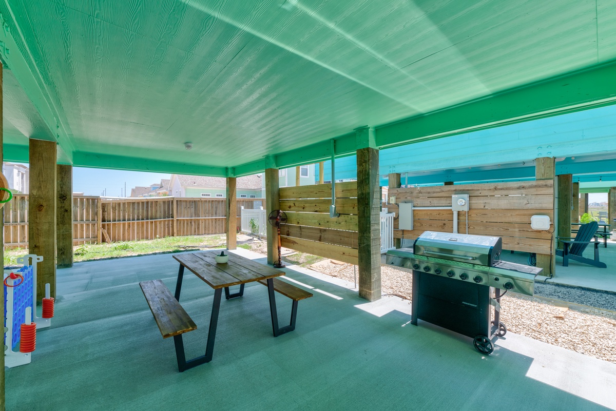 Your covered patio offers the perfect setup for outdoor dining and grilling, with a picnic table and BBQ ready for memorable meals under the bright green roof.
