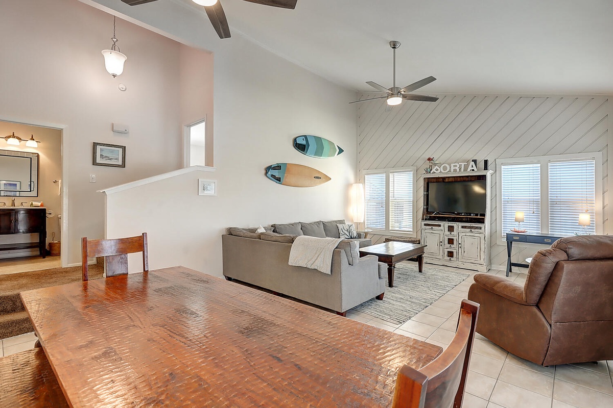Unwind in your spacious coastal living area where surfboards and comfortable seating create the perfect beach house atmosphere.