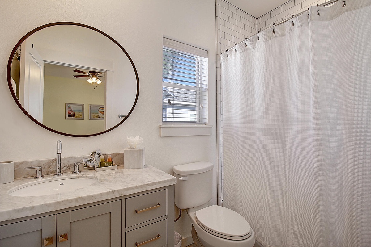 Step into your beautifully appointed bathroom where marble countertops and a striking round mirror create an elegant atmosphere for your morning routine.