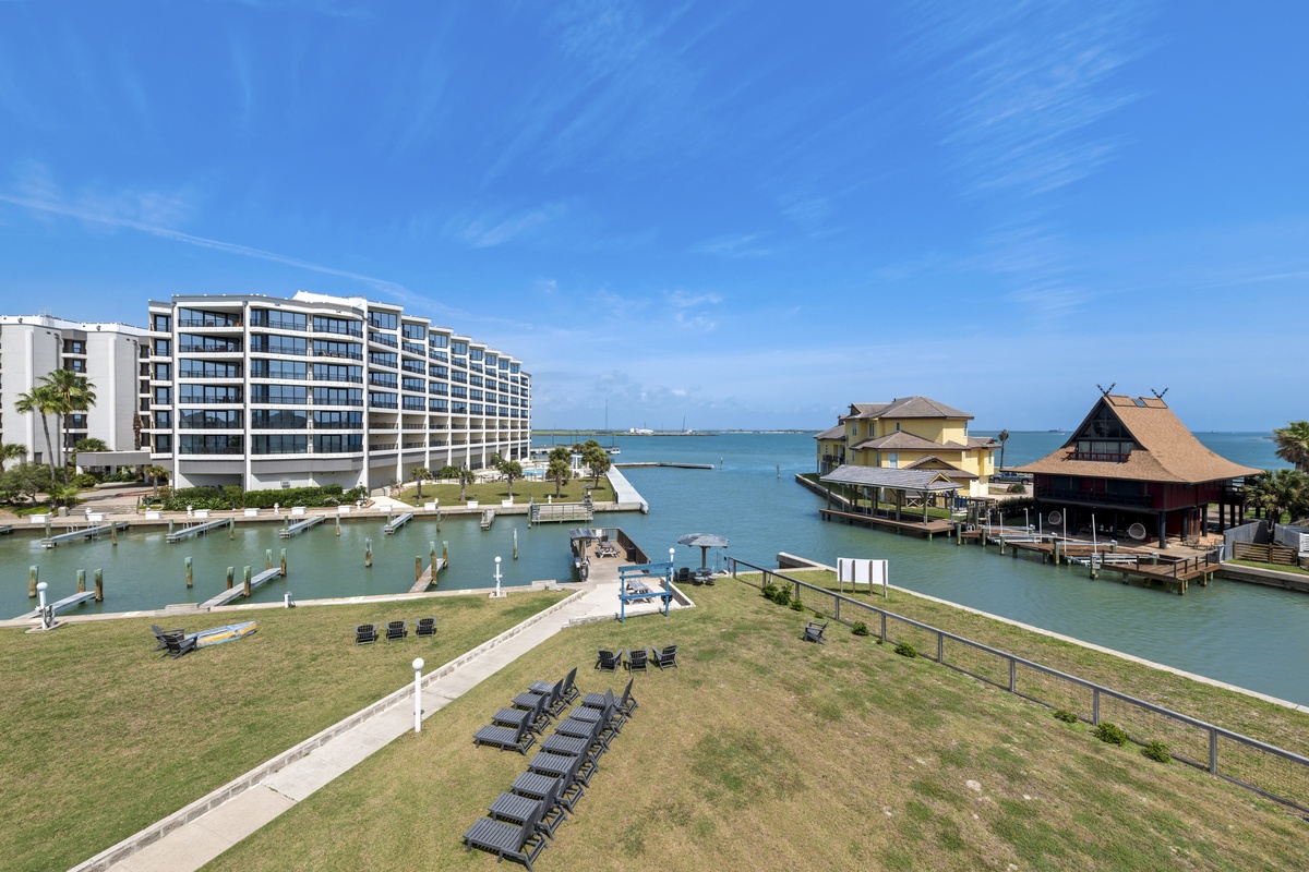 Modern waterfront resort complex situated on tropical coastline with marina facilities and traditional-style buildings overlooking crystal-clear waters.