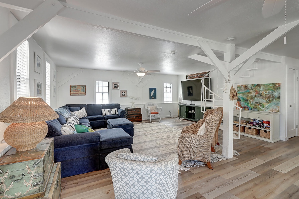 Unwind in your bright, airy living space with exposed beams, plush navy sectional, and coastal charm throughout.