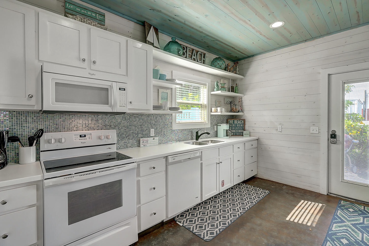Your fully equipped beach-style kitchen features white cabinets, coastal decor, and everything you need to create memorable meals during your stay.