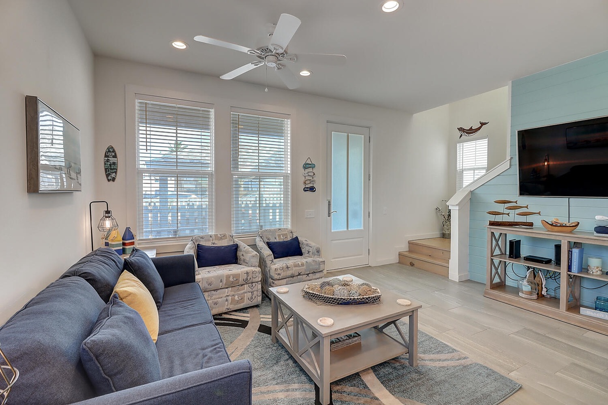 Sink into plush coastal-themed seating while the ceiling fan keeps you cool. Your beachside retreat awaits with nautical touches and modern comfort.