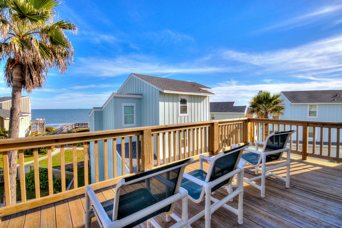Relax on your private deck with ocean views, where comfortable lounge chairs invite you to unwind under swaying palms.