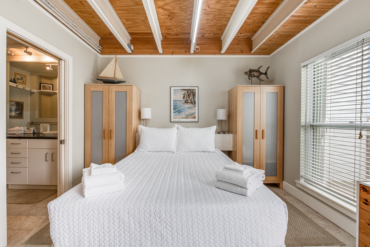 Rest in your coastal haven with crisp white linens, warm wood ceiling beams, and nautical touches creating the perfect beach retreat.