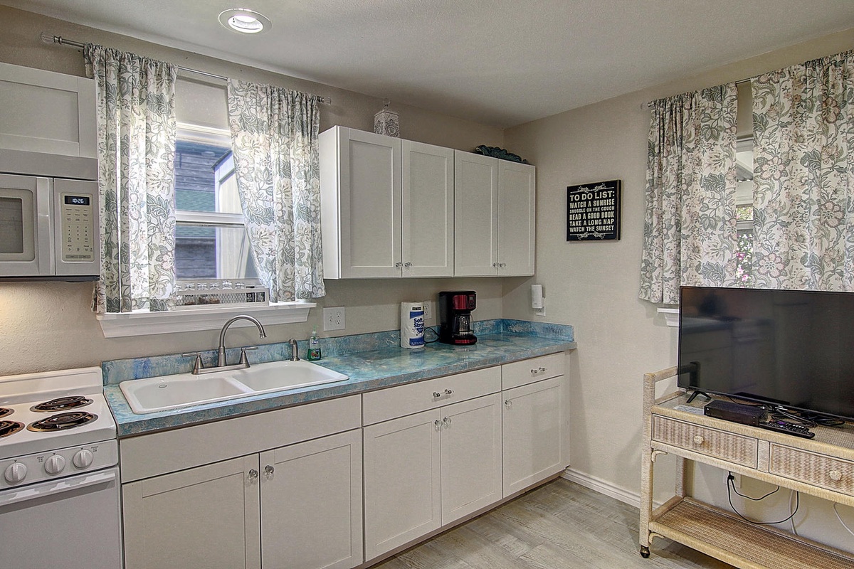 Prepare your favorite meals in this fully equipped kitchen featuring white cabinets, marble countertops, and all the essentials for a comfortable stay.