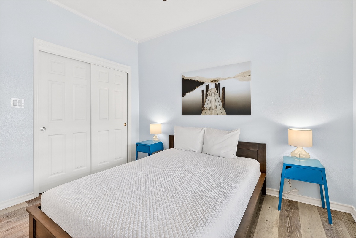 Your peaceful bedroom features crisp white linens, warm bedside lighting, and stylish blue accents that create the perfect atmosphere for restful nights.