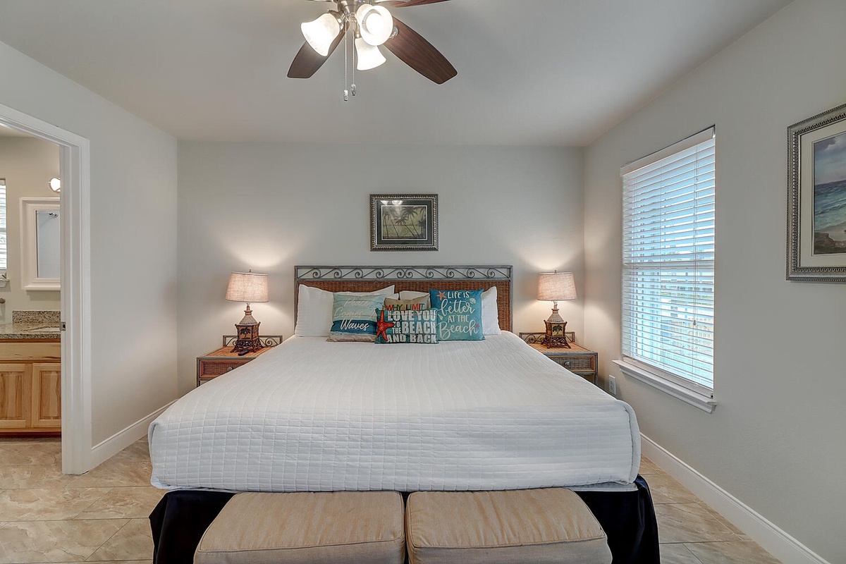 Unwind in your bright master bedroom, where coastal-themed pillows and warm bedside lighting create the perfect retreat after beach adventures.