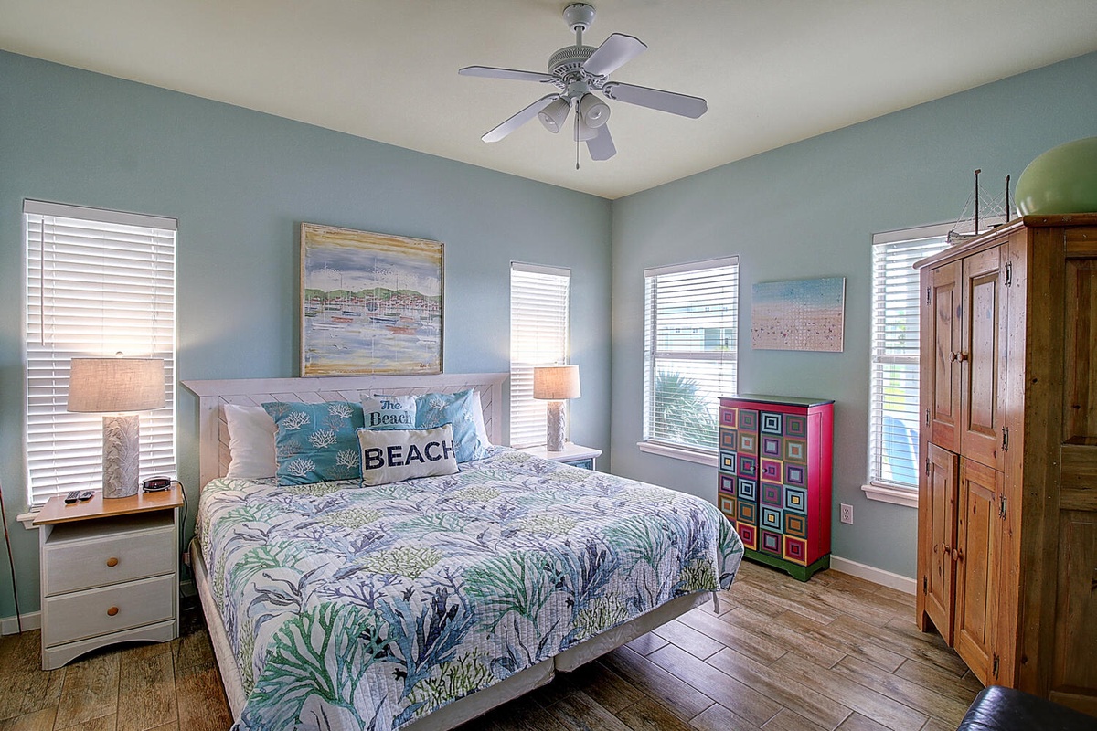 Drift off in your coastal bedroom where soft blue walls and tropical bedding create a soothing beach retreat with plenty of natural light.