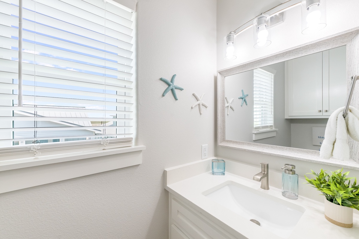 Refresh in your pristine coastal bathroom featuring a soaking tub, marble countertops, and charming starfish accents that bring seaside tranquility indoors.