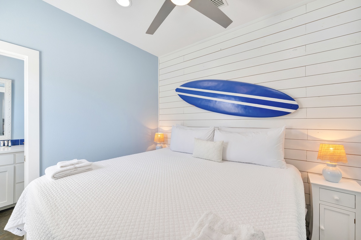 Rest easy in your coastal-themed bedroom, where crisp white linens and warm bedside lighting create the perfect retreat after beach adventures.