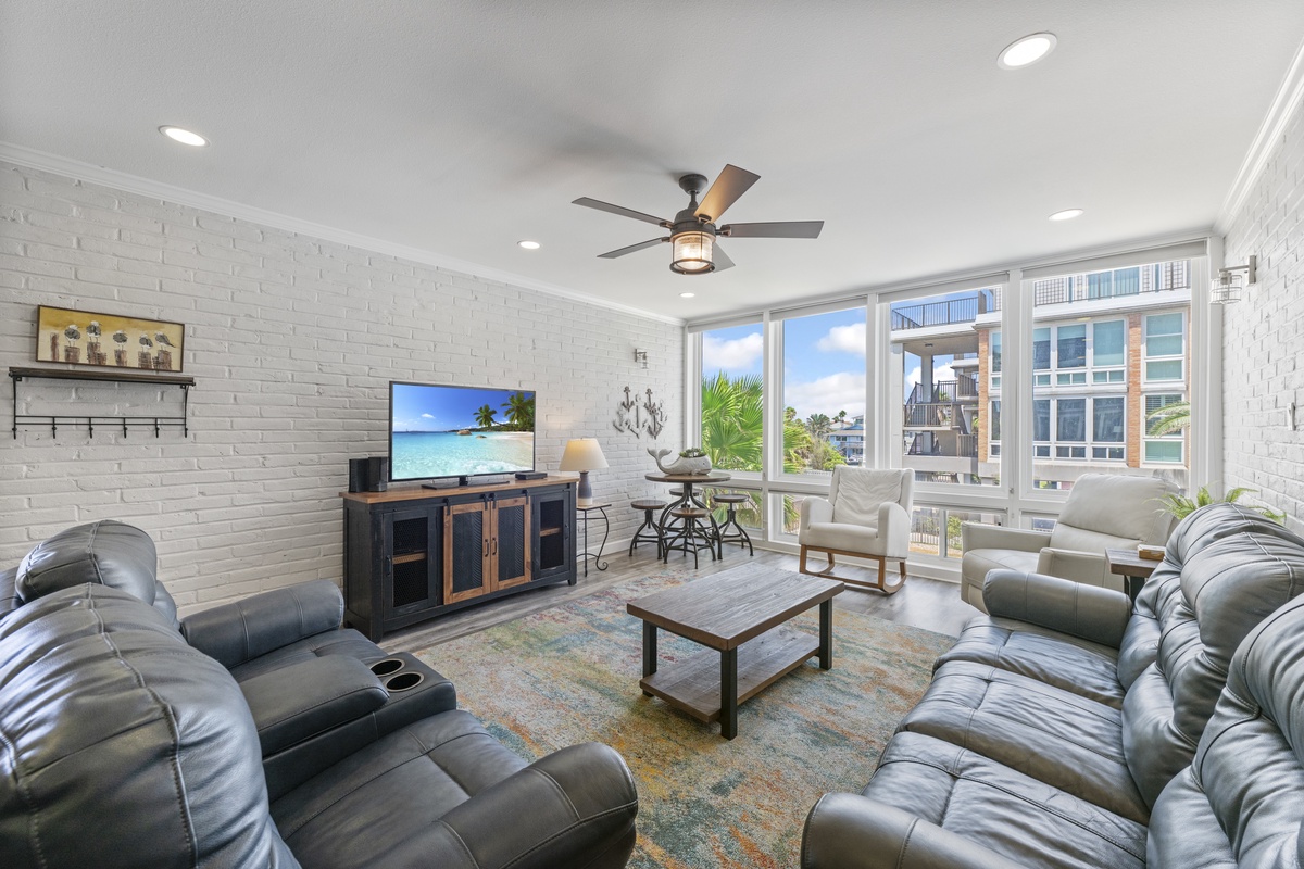Relax in your stylish living room with plush leather seating, exposed brick walls, and large windows flooding the space with natural light.
