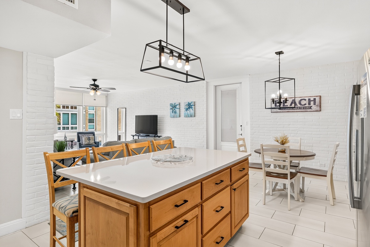 Gather around the spacious kitchen island for meals and conversation in this bright, open-plan living space with modern fixtures and coastal charm.